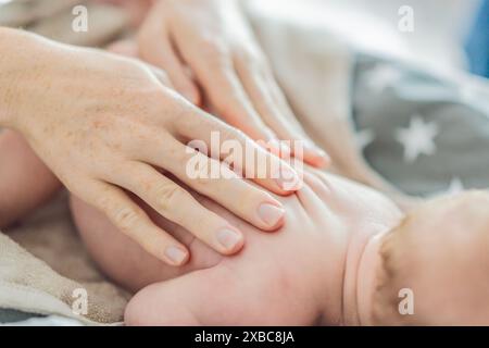 La pelle del neonato si sta staccando. La mamma utilizza prodotti per la pelle e massaggi per curare e lenire la delicata pelle del bambino, garantendo comfort e promozione Foto Stock