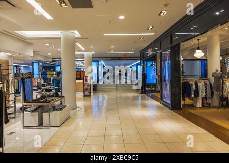 Splendidi interni di Macy's a New York City, con varie esposizioni di abbigliamento e una guardia di sicurezza al centro della sala. New York. STATI UNITI. Foto Stock