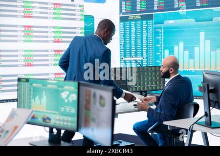 Responsabile finanziario che informa i membri del suo team sui nuovi obiettivi aziendali, presentando il loro schema di budget con le spese. Allocazione delle risorse e pianificazione dei progetti nella sala di controllo. Foto Stock