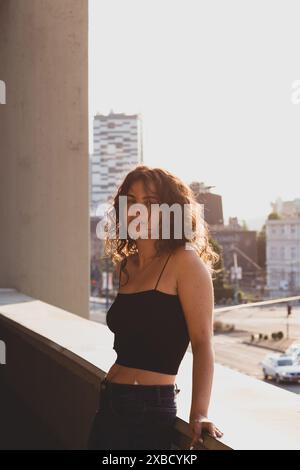 Ragazza in piedi sul balcone al sole Foto Stock