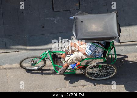 Un uomo guida un triciclo per disabili lungo la strada, Saigon, Vietnam Foto Stock