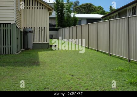 Vista sul cortile laterale di una casa del dopoguerra a Brisbane in condizioni originali, pannelli in legno e spranghe in legno per la ventilazione sotto casa, semi aperte Foto Stock