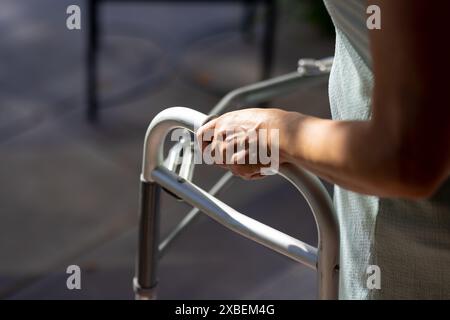 Donna asiatica matura che usa il camminatore per il sostegno, a casa Foto Stock