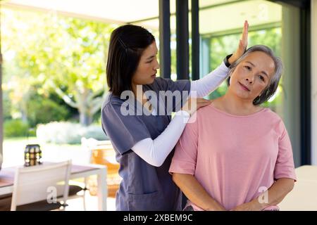 Fisioterapista che assiste donna asiatica anziana con esercizi di fisioterapia. Assistenza sanitaria aiutare casa e terapia fisica pensione inalterato in bri Foto Stock