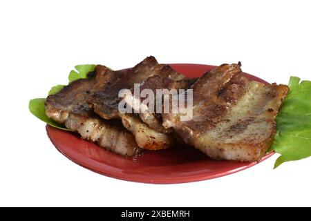 Su un piatto giacciono diverse fette di pancetta fritta. Foto Stock