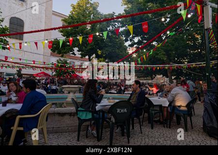 Le persone si godono pasti e bevande al jardim da grazia durante le popolari festività dei santi, seduti sotto gli ombrelloni colorati e sagres Foto Stock