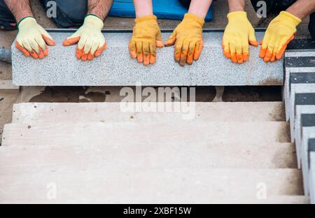 Passi concreti in costruzione come un team di costruttori installare blocchi di cemento pesanti Foto Stock