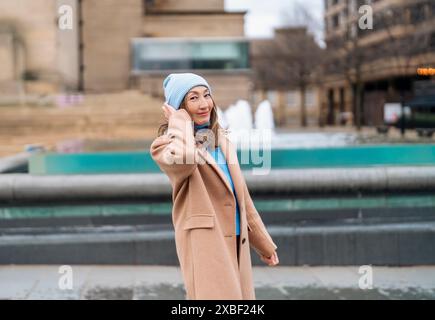 sorridente donna asiatica felice che si diverte e cammina per una città il giorno di primavera Foto Stock