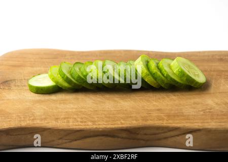 fetta di cetriolo su un tagliere di legno, isolato su sfondo bianco Foto Stock