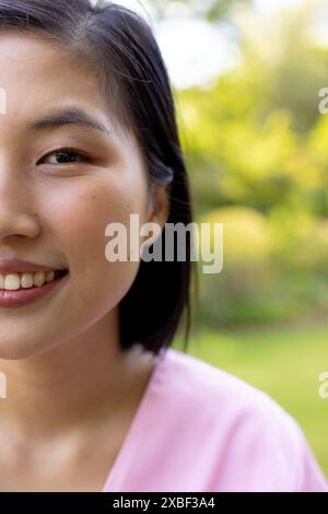 Giovane donna asiatica sorridente calorosamente, fuori in giardino, a casa Foto Stock