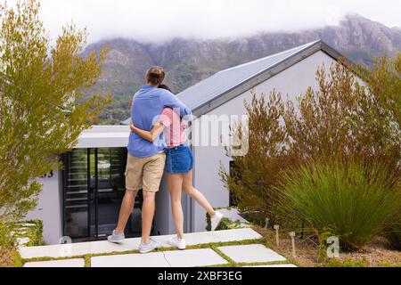 Diverse coppie si abbracciano mentre guardano la loro casa moderna Foto Stock