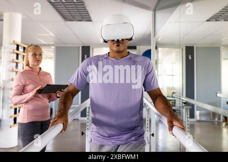 Uomo birazziale che indossa un visore VR utilizzando barre parallele per la riabilitazione Foto Stock