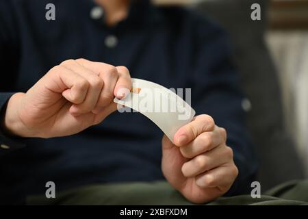 Primo piano un giovane turbato che rompe la carta di credito. Problemi finanziari e concetto di assenza di debito Foto Stock