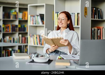 Una donna rossa infilata in un libro, circondata da scaffali di libri in una biblioteca, assorbendo la conoscenza. Foto Stock