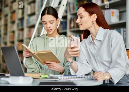 un tutor con la testa rossa e una ragazza adolescente, immersi in un libro a un tavolo della biblioteca, imparando insieme. Foto Stock