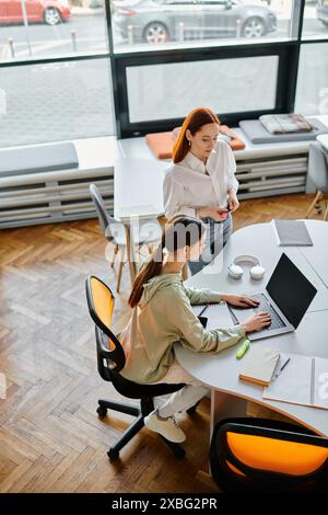 uno è un tutor e l'altro uno studente, si impegnano in lezioni dopo la scuola utilizzando i computer portatili in un ambiente di ufficio moderno. Foto Stock