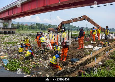 West Bandung Regency, Indonesia. 12 giugno 2024. Gli ufficiali che utilizzano un escavatore anfibio ripuliscono i rifiuti di plastica che si sono depositati nel fiume Citarum a Batujajar, West Bandung Regency, West Java, Indonesia il 12 giugno 2024. Sulla base del servizio per l’ambiente e l’igiene della provincia occidentale, i registri dei rifiuti bloccati nel flusso fluviale da venerdì 7 giugno 2024 nella zona del fiume Citarum Batujajar, che è lungo 3 chilometri e largo 60 metri, si stima che il volume dei rifiuti di plastica potrebbe raggiungere oltre 100 tonnellate. (Foto di Dimas Rachmatsyah/Sipa USA) credito: SIPA USA/Alamy Live News Foto Stock