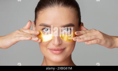 Donna che indossa toppe dorate per gli occhi, primo piano Foto Stock