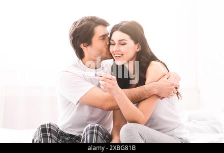 Coppia felice che condivide eccitanti notizie di gravidanza a letto, abbracciando Foto Stock