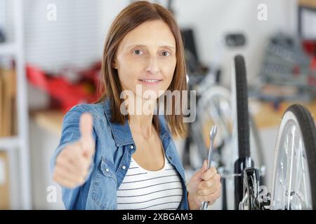 giovane donna con la bici che mostra il pollice in su Foto Stock