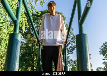 Young Man che fa immersioni al Parallel Bar nel Park il giorno della domenica Foto Stock
