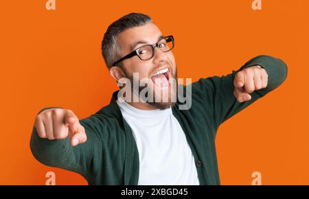 Uomo che indossa occhiali e Green Cardigan che punta alla fotocamera Foto Stock