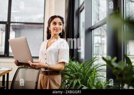 donna indiana in piedi davanti alla finestra con un portatile. Foto Stock