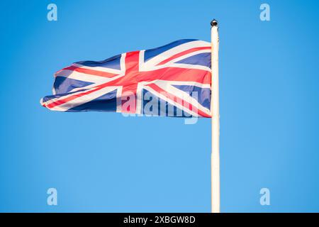Bandiera del Regno Unito immersa nella storia, ondate contro il cielo azzurro, lo spirito duraturo e la ricca eredità del Regno Unito, Union Jack Foto Stock