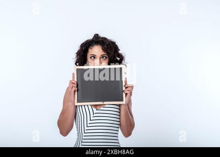 Una giovane donna d'affari, fiduciosa e accogliente, sorridente, ha un cartello con la lavagna con spazio per lo slogan pubblicitario o la messaggistica di concetto chiave. Copia spazio Foto Stock