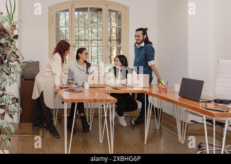 Un gruppo di imprenditori diversi collabora a un progetto comune con entusiasmo e motivazione in un ufficio luminoso. Foto Stock