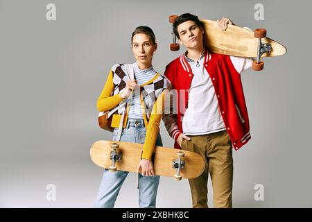 Due giovani tengono gli skateboard su uno sfondo grigio. Foto Stock
