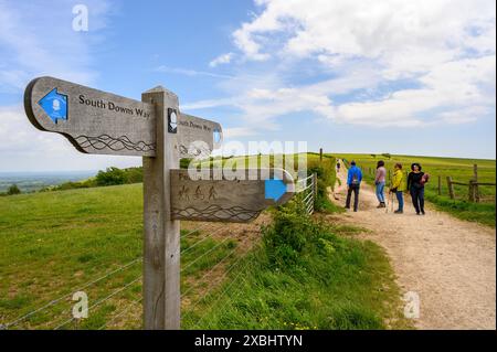 Cartello in legno con tre direzioni su South Downs Way con un gruppo di camminatori vicino a Clayton, West Sussex, Inghilterra. Foto Stock