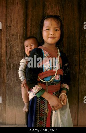 Hmong Hill Tribe, Thailandia settentrionale, Asia sudorientale. La giovane ragazza, la sua sorellina, urla in una fionda sulla schiena del villaggio Pa Kludy anni '1990, circa 1995 HOMER SYKES Foto Stock