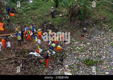 West Bandung Regency, Indonesia. 12 giugno 2024. Foto aerea degli ufficiali che puliscono mucchi di rifiuti nel fiume Citarum Batujajar, West Bandung Regency, West Java, Indonesia, il 12 giugno, 2024. si stima che il mucchio di rifiuti nel fiume Citarum, nell'area del distretto di Batujajar, sia lungo 3 chilometri e largo 60 metri, con un volume stimato di rifiuti di plastica superiore a 100 tonnellate. (Foto di Rasyad Yahdiyan/INA Photo Agency/Sipa USA) credito: SIPA USA/Alamy Live News Foto Stock