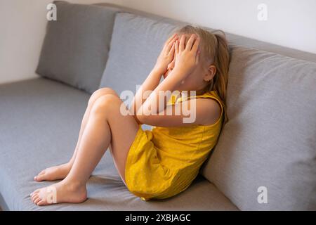 bambino piccolo di 5 anni, ragazza bionda piange, coprendo il viso, diagnosi precoce e intervento, capriccio infantile, persone con autismo, atteggiamento protettivo, co Foto Stock