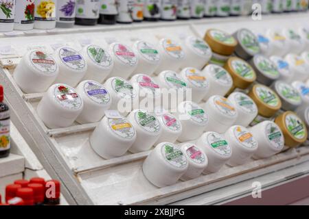 Osijek Croazia - 7 06 2024: Fiera della salute e della bellezza. esposizione di piccoli vasi di panna, possibilmente fatti a mano o biologici, disposti in file su ripiani bianchi a. Foto Stock