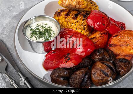 Verdure grigliate su un piatto, mais e peperoni, funghi e salsa. Copia spazio Foto Stock