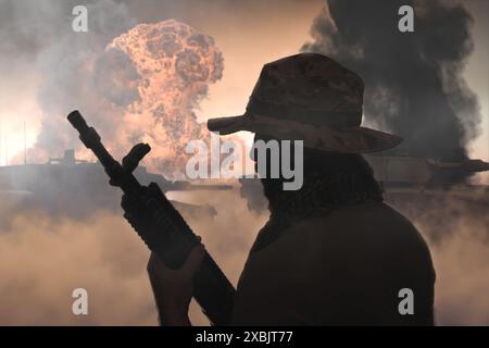 Un soldato militare con una mitragliatrice sullo sfondo di carri armati in fiamme, fuoco e fumo. Concetto: Guerra in Medio Oriente, Foto Stock