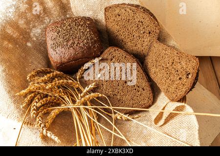 Una pagnotta di pane Borodino nero e fette tagliate su tela e un orecchio di segale. Foto di alta qualità Foto Stock