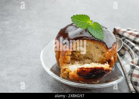 Rum baba decorato con cioccolato fondente su sfondo grigio Foto Stock