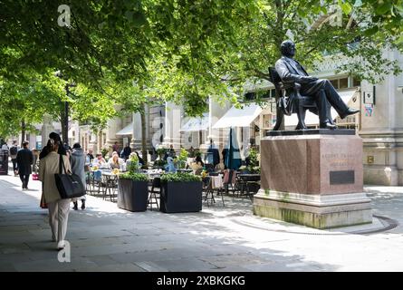 Persone che cenano all'aperto ai tavoli sul marciapiede di Royal Exchange Avenue. Statua di George Peabody in primo piano. Città di Londra Inghilterra Regno Unito Foto Stock