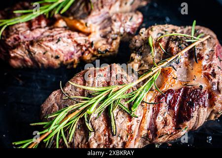 La bistecca di manzo marmorizzata con rosmarino è grigliata. Primo piano. Foto di alta qualità Foto Stock
