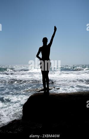 Silhouette di giovane donna in Bikini di fronte al mare sulla spiaggia Foto Stock