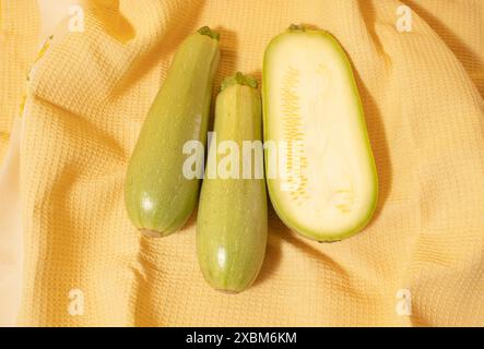 Zucchine verdi fresche su sfondo giallo. Foto Stock