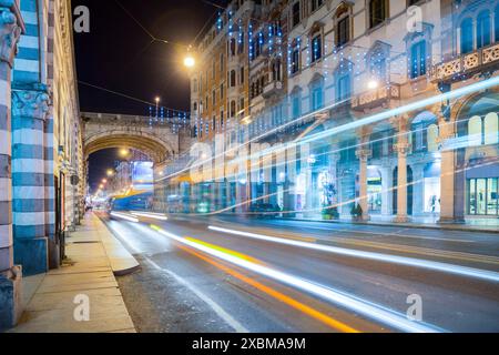 Via principale a lunga esposizione con traffico ed edifici di notte con sentieri leggeri nella città di Genova, Liguria, Italia Foto Stock