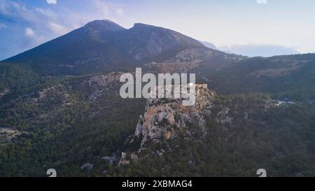 Drone shot, Un castello su una grande collina con montagne sullo sfondo al crepuscolo, Kastro Monolithou, il castello di Monolithos, il castello di roccia, il villaggio di Monolithos Foto Stock