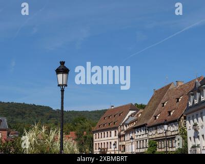 Lampione di fronte a una fila di case tradizionali con verdi colline sullo sfondo, Wissembourg, Alsazia, Francia Foto Stock