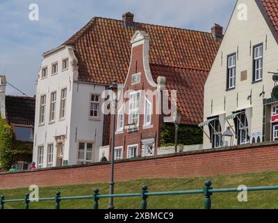 Fila di edifici storici con tetti di tegole rosse e facciate bianche sotto un cielo azzurro, Greetsiel, Frisia orientale, bassa Sassonia, Germania Foto Stock