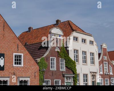 Case storiche con facciate in mattoni e tetti piastrellati, alcune ricoperte di piante rampicanti, greetsiel, frisia orientale, germania Foto Stock