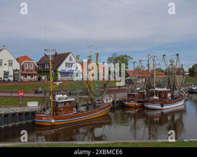 Le barche da pesca sono ancorate nel porto, nelle case sullo sfondo e in un'atmosfera marittima, Greetsiel, Frisia orientale, bassa Sassonia, Germania Foto Stock